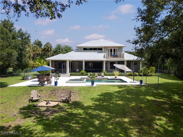 rear view of house featuring a sunroom, a yard, a fire pit, a balcony, and a patio area