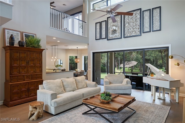 living room featuring ceiling fan, light hardwood / wood-style floors, and a high ceiling