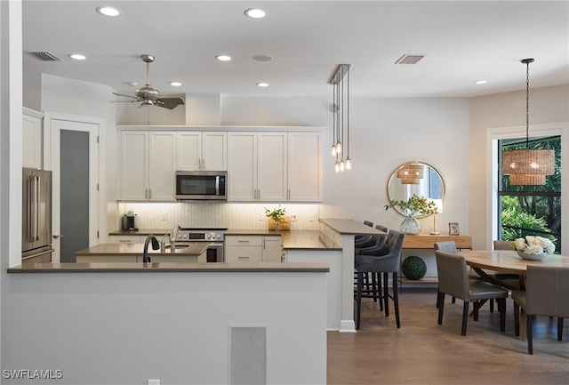 kitchen featuring kitchen peninsula, white cabinetry, hanging light fixtures, and premium appliances