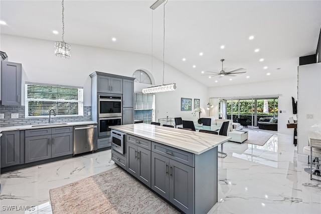 kitchen featuring appliances with stainless steel finishes, ceiling fan, gray cabinets, and a wealth of natural light