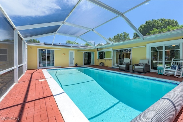 view of pool featuring glass enclosure, an outdoor hangout area, and a patio area