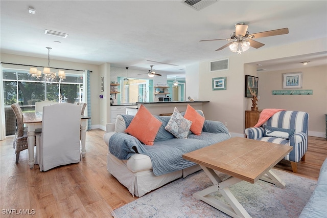 living room featuring ceiling fan with notable chandelier and light hardwood / wood-style floors