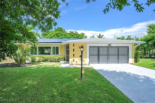 ranch-style home with solar panels, a front yard, and a garage