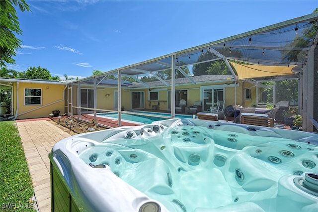 view of pool featuring glass enclosure, a patio, and a hot tub