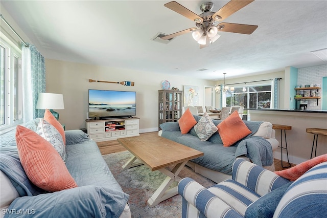 living room featuring ceiling fan with notable chandelier, hardwood / wood-style floors, and a wealth of natural light