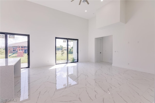 unfurnished room with ceiling fan, plenty of natural light, and a high ceiling