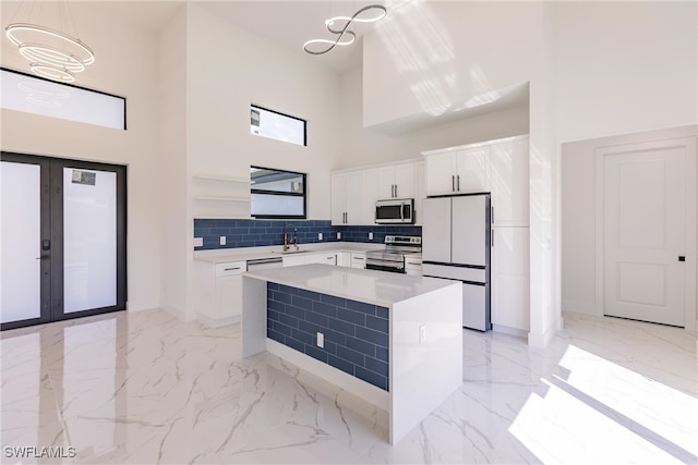 kitchen featuring tasteful backsplash, decorative light fixtures, white cabinetry, stainless steel appliances, and a center island