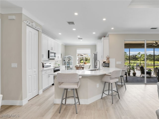 kitchen featuring a breakfast bar, white cabinets, kitchen peninsula, stainless steel appliances, and sink