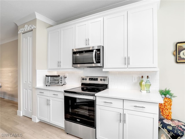 kitchen with appliances with stainless steel finishes, white cabinets, backsplash, light wood-type flooring, and ornamental molding