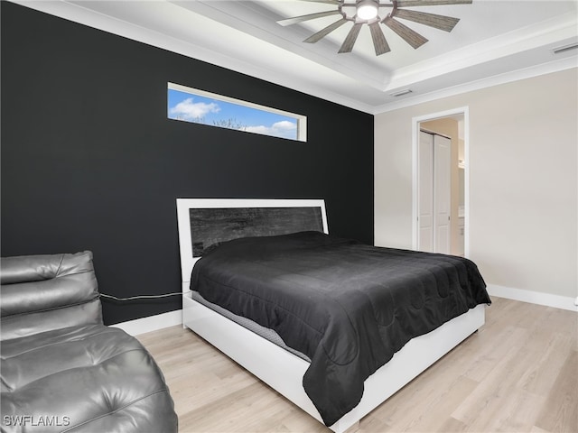 bedroom with crown molding, a raised ceiling, ceiling fan, and light hardwood / wood-style flooring