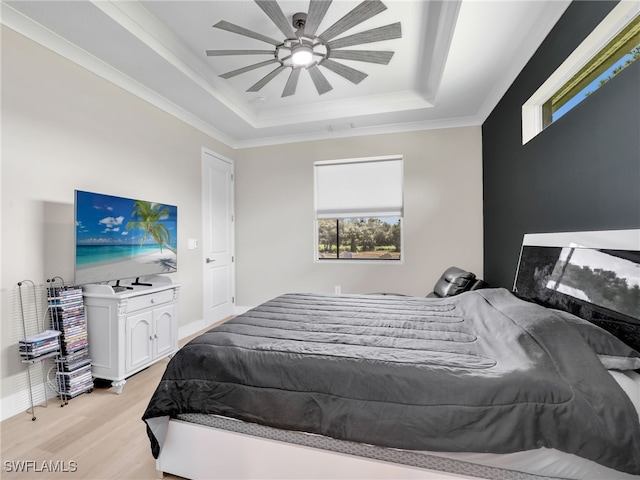 bedroom featuring ceiling fan, ornamental molding, a raised ceiling, and light hardwood / wood-style floors