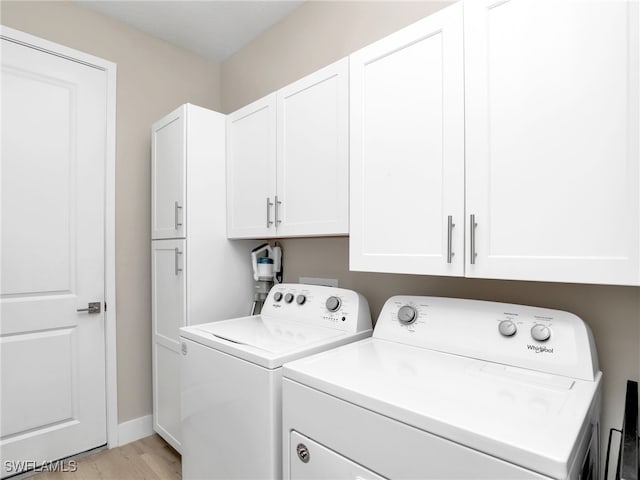 laundry room featuring cabinets, light wood-type flooring, and washing machine and clothes dryer