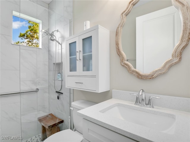 bathroom with tiled shower, vanity, and toilet