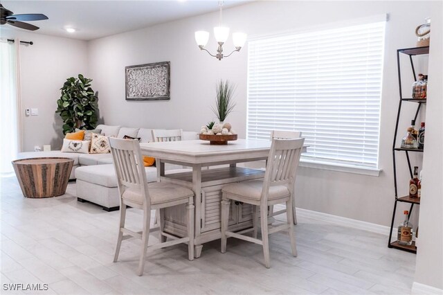 dining room featuring ceiling fan with notable chandelier and light hardwood / wood-style floors