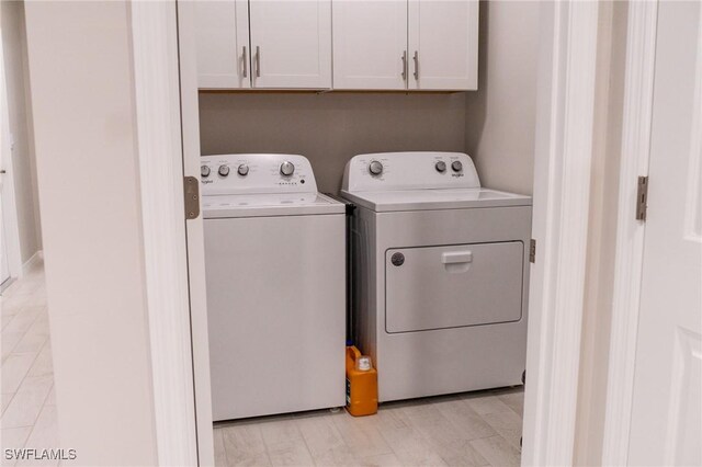 laundry room featuring washer and clothes dryer and cabinets