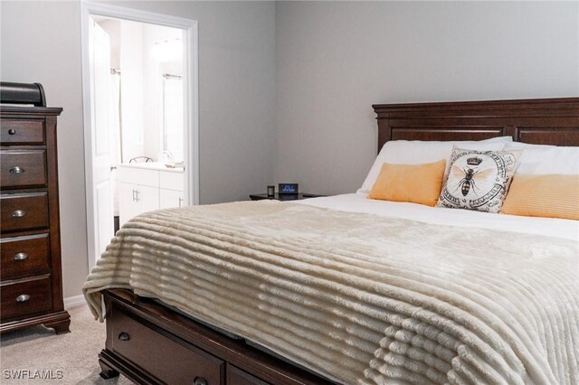 bedroom with connected bathroom and light colored carpet