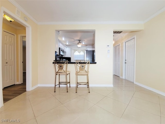 kitchen featuring crown molding, a kitchen bar, kitchen peninsula, and stainless steel appliances