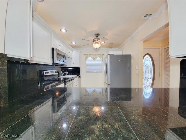 kitchen with a healthy amount of sunlight, white cabinets, stainless steel appliances, and ornamental molding