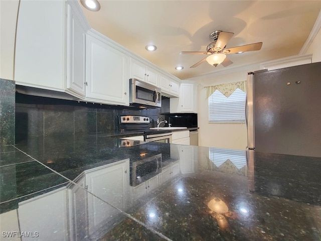 kitchen featuring appliances with stainless steel finishes, tasteful backsplash, ornamental molding, dark stone countertops, and white cabinets