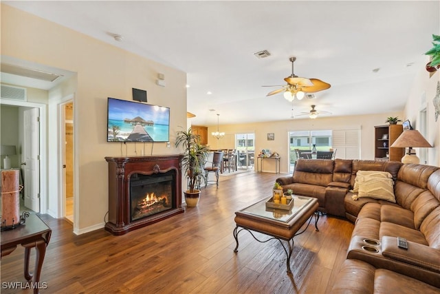 living area featuring baseboards, visible vents, wood finished floors, and a ceiling fan