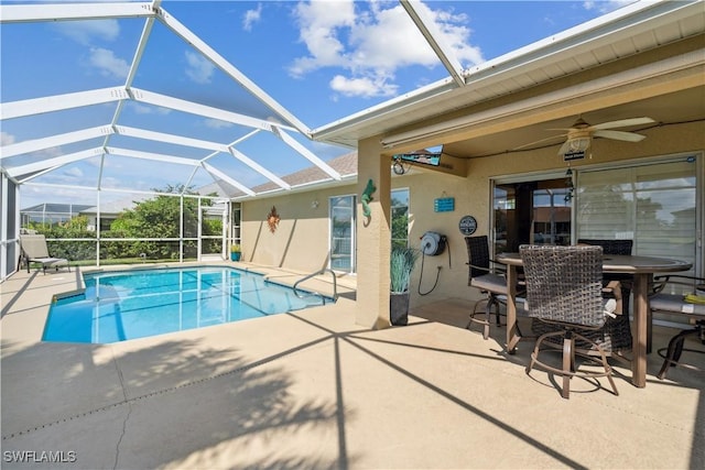 outdoor pool featuring a patio, ceiling fan, and glass enclosure