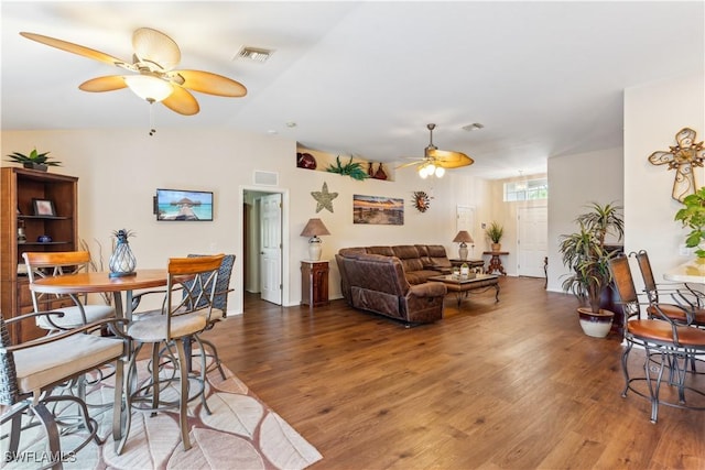 living room with visible vents, wood finished floors, a ceiling fan, and vaulted ceiling