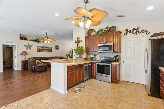 kitchen featuring stainless steel appliances, ceiling fan, open floor plan, and a peninsula