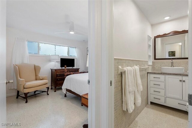 bedroom featuring tile walls, ceiling fan, and sink