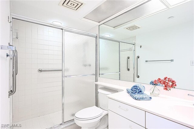 bathroom featuring toilet, vanity, and a shower with shower door