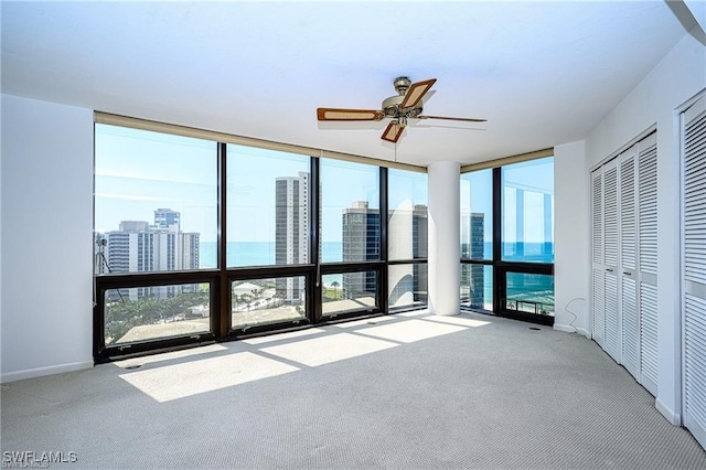 interior space featuring a water view, ceiling fan, and a wall of windows