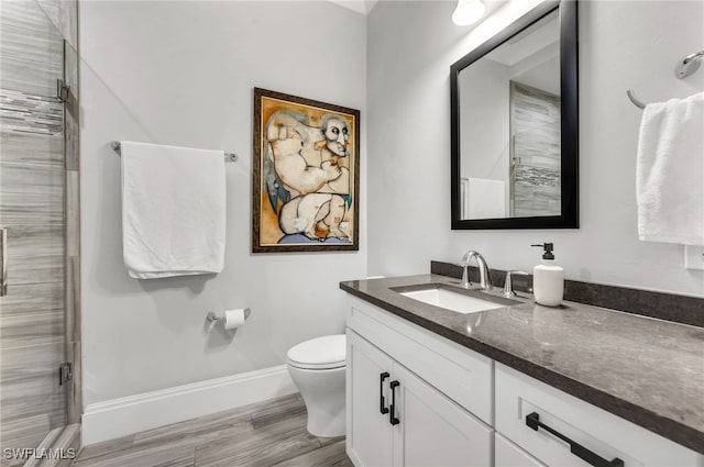 bathroom with wood-type flooring, vanity, toilet, and a shower with door