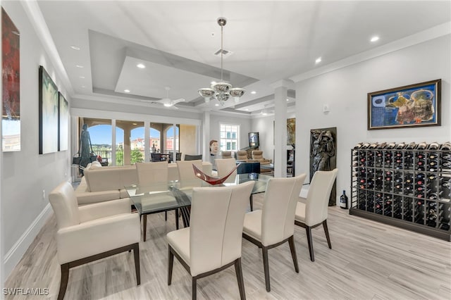 dining area with light hardwood / wood-style flooring, a raised ceiling, ceiling fan with notable chandelier, and crown molding