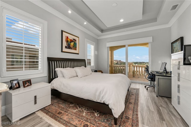 bedroom featuring a tray ceiling, light hardwood / wood-style floors, and access to outside