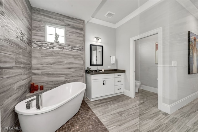 bathroom featuring tile walls, a bathing tub, vanity, and toilet