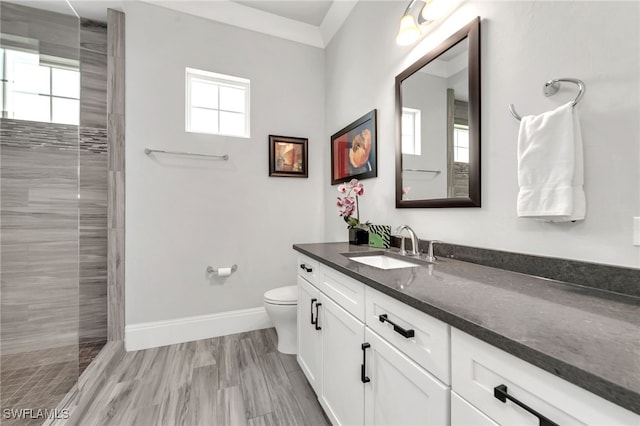 bathroom featuring vanity, hardwood / wood-style floors, toilet, and tiled shower