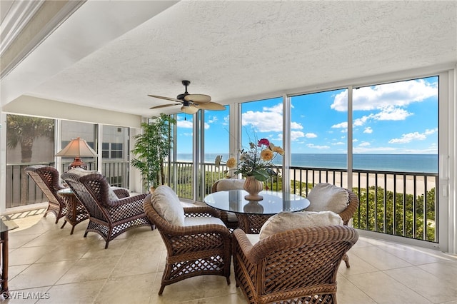 sunroom / solarium featuring a view of the beach, a water view, and ceiling fan