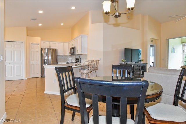 tiled dining room with sink, a chandelier, and lofted ceiling