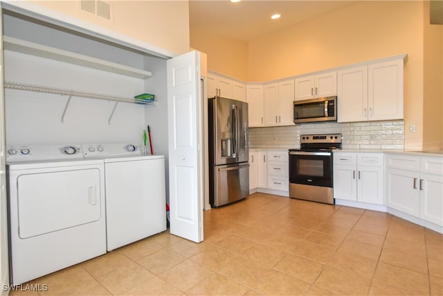 kitchen with white cabinets, appliances with stainless steel finishes, independent washer and dryer, and light tile patterned floors