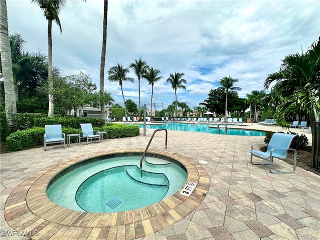 view of swimming pool featuring a patio and a hot tub