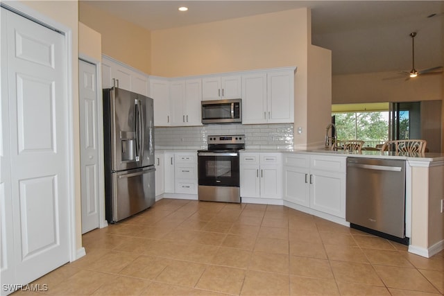 kitchen with white cabinets, stainless steel appliances, ceiling fan, and light tile patterned flooring