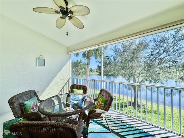 sunroom with ceiling fan and a water view