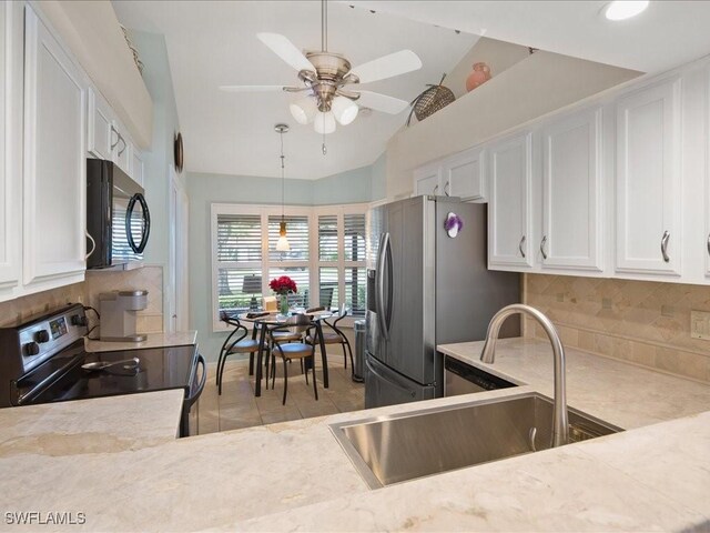 kitchen featuring lofted ceiling, range with electric stovetop, sink, white cabinetry, and stainless steel refrigerator