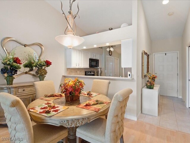 dining area featuring light wood-type flooring and high vaulted ceiling