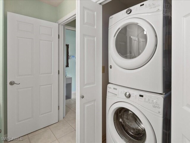 laundry area with light tile patterned floors and stacked washer and clothes dryer