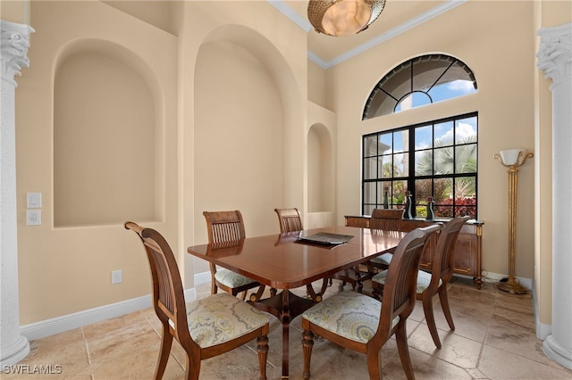 dining room featuring decorative columns, crown molding, and a high ceiling