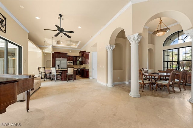 interior space with a high ceiling, decorative columns, ornamental molding, and ceiling fan