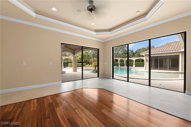 spare room with ceiling fan, hardwood / wood-style flooring, a tray ceiling, and crown molding