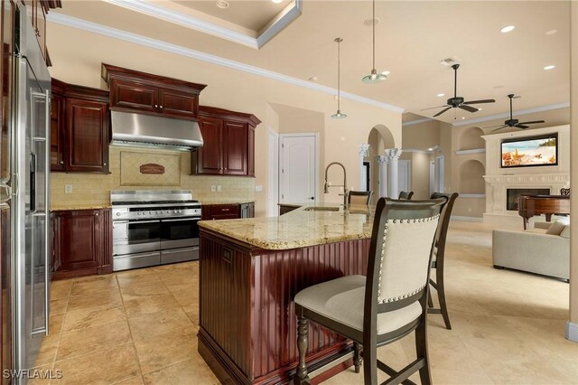 kitchen featuring sink, stainless steel gas range oven, hanging light fixtures, ornamental molding, and ceiling fan