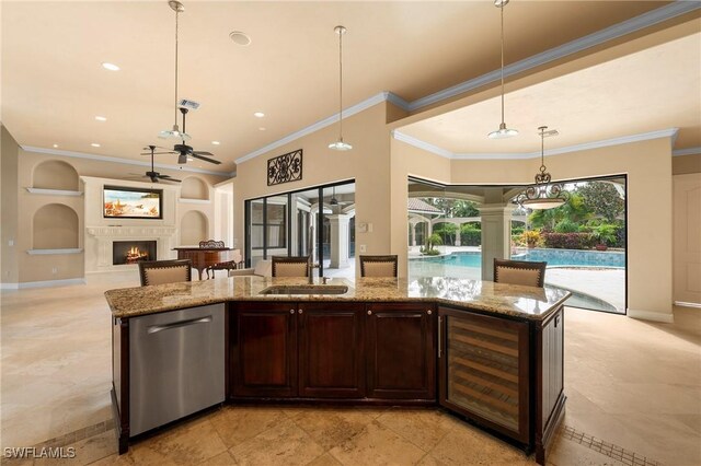 kitchen with an island with sink, pendant lighting, dark brown cabinets, stainless steel dishwasher, and ornamental molding