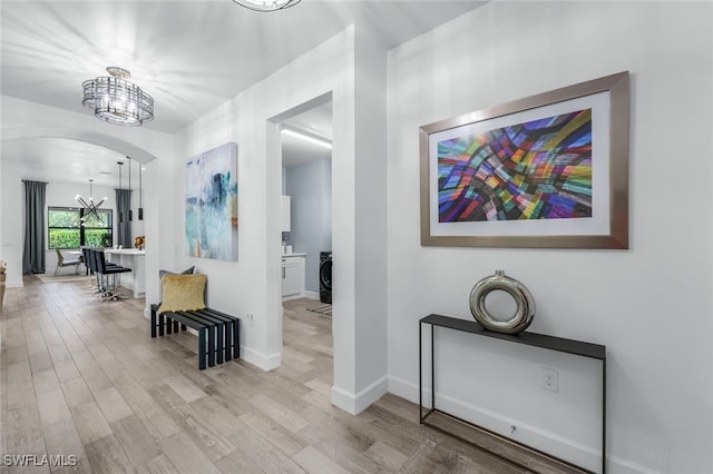 hallway featuring a notable chandelier and light hardwood / wood-style flooring